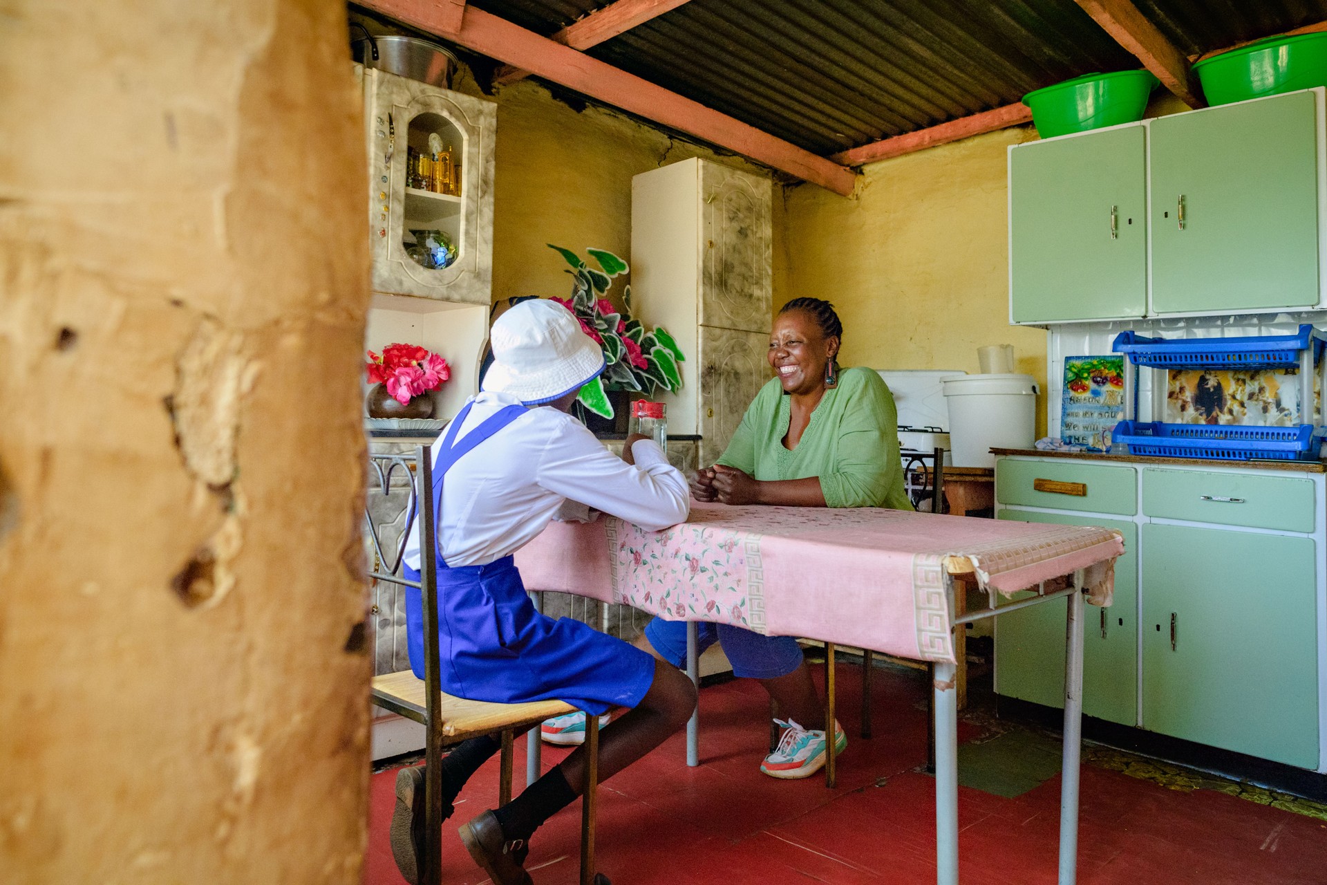 Woman and schoolgirl in rural home kitchen sitting at table having lunch together